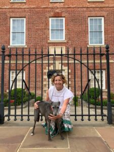 Sammie and Doris a grey lurcher standing in front of a large gate